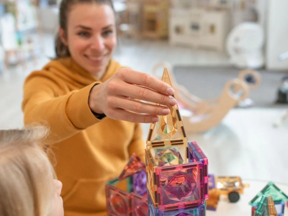 Moteris kartu su vaiku stato bokštą iš magnetinių detalių