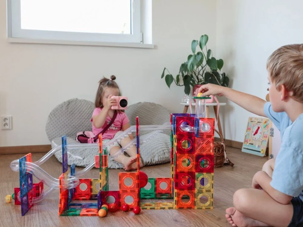 Berniukas paleidžia kamuoliuką, mergaitė fotografuoja trasą
